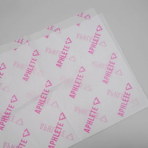 May include: White tissue paper with a pink heart and the word "APHLETE" repeated throughout.