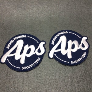 May include: Two blue and white embroidered patches with the text "Award Winning Aps Shopfitters" in a circle.
