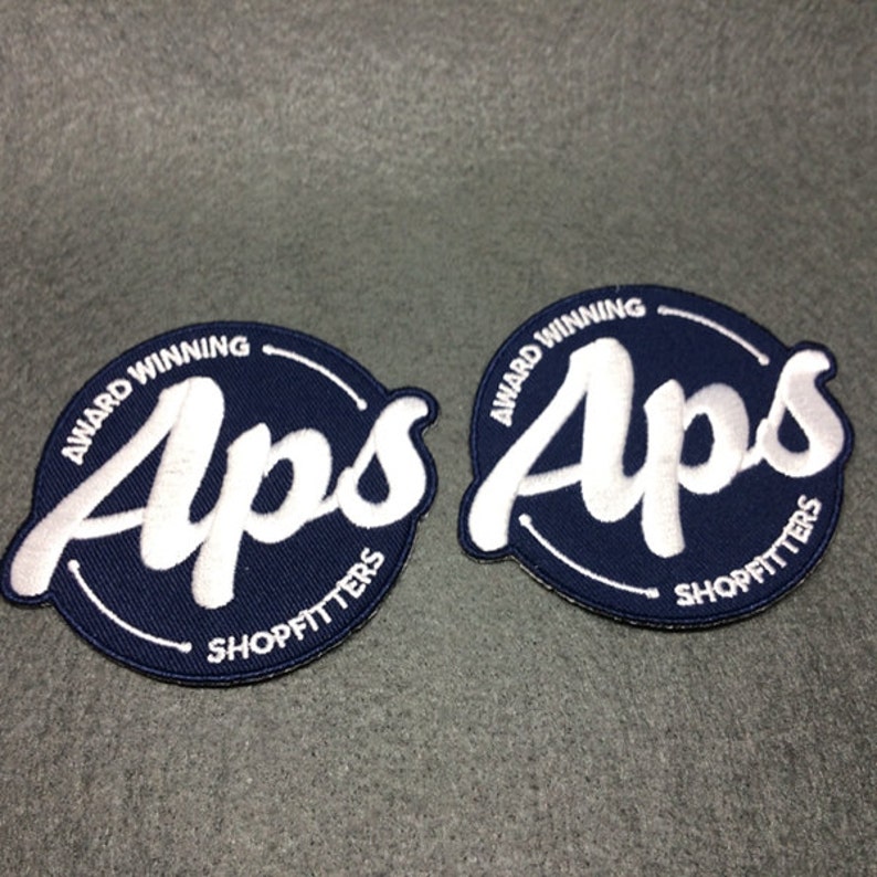 May include: Two blue and white embroidered patches with the text "Award Winning Aps Shopfitters" in a circle.