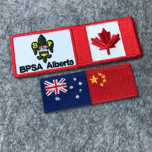 May include: Two embroidered patches. The top patch is white with a green and gold emblem and the text "BPSA Alberta". The bottom half of the patch is red with a white Canadian flag. The bottom patch is blue with a white Southern Cross and a red field with a yellow five-pointed star and four smaller stars.