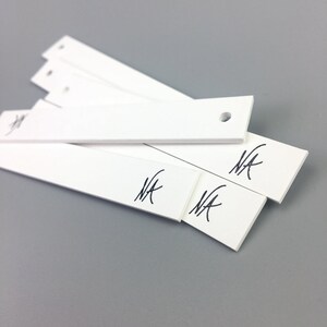 May include: Four white rectangular scent strips with a hole in the top and the word "NA" written on each strip.