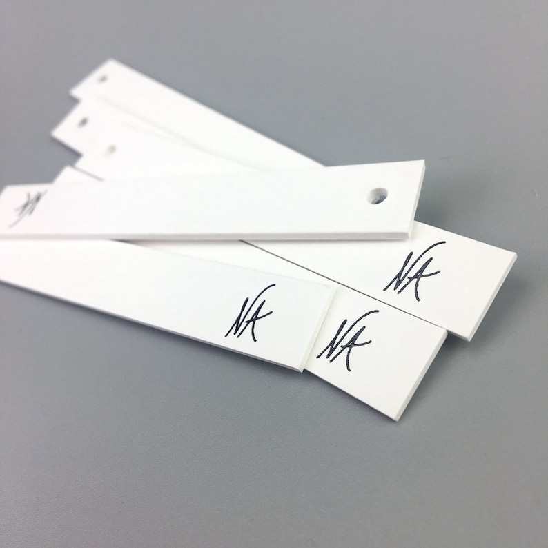 May include: Four white rectangular scent strips with a hole in the top and the word "NA" written on each strip.