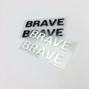 以下が含まれることがあります： 黒と白で「BRAVE」と印刷されたアイロン接着パッチが4つ。パッチは透明なプラスチックの裏地が付いています。
