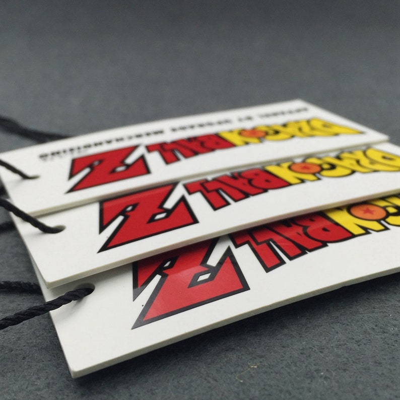 May include: Three white hang tags with black string. Each tag features a red and yellow graphic of the Dragon Ball Z logo with the text "Dragon Ball Z" printed in black.