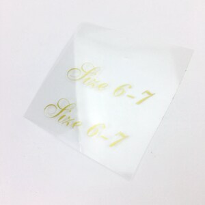 May include: Two clear plastic stickers with gold lettering that reads "Size 6-7".