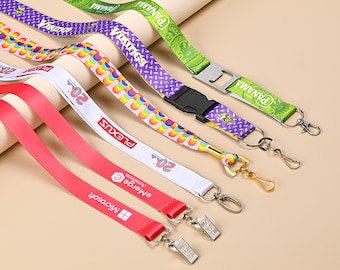 May include: A collection of colorful printed lanyards with various company logos and text, including "Microsoft", "Plexus", "Panama", "Virtuos", and "emerge. empower." The lanyards have different types of attachments, including a bottle opener, a swivel clip, and a lobster claw clasp.