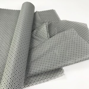May include: A roll of white tissue paper with a black geometric pattern. The paper is folded and arranged on a white surface.