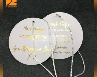 May include: Two white round gift tags with gold lettering. The tag on the left says "This package was wrapped by from Bahamas with love XX". The tag on the right says "Beach Rules: Soak up the sun! The waves are for the salty air Sandcastles protect are required".