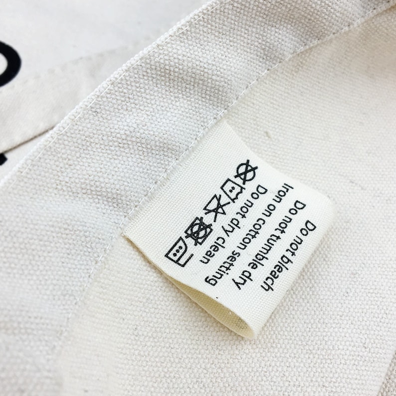 May include: A white fabric care label with black text and symbols. The label says "Do not bleach", "Do not tumble dry", "Iron on cotton setting", and "Do not dry clean".