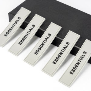 May include: Five gray rectangular labels with the word "ESSENTIALS" printed in black on each label.