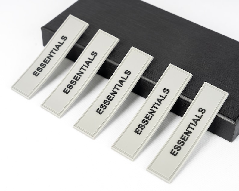 May include: Five gray rectangular labels with the word "ESSENTIALS" printed in black on each label.