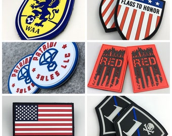 Puede incluir: Surtido de parches bordados con varios diseños, incluyendo un logotipo de club de fútbol, un diseño patriótico con las palabras "Patriot Sales LLC", una bandera estadounidense roja, blanca y azul, un parche rojo con la palabra "RED" y un diseño de temática militar, y un parche blanco y negro con una calavera y huesos cruzados.