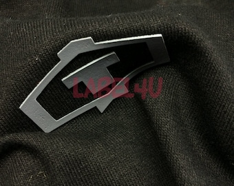 May include: A gray fabric patch with a geometric design. The patch has a cut-out shape that resembles a letter "T".