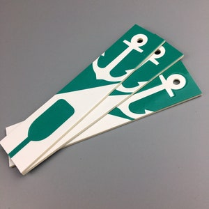 May include: Three white bookmarks with a green background and a white anchor design. The bookmarks are stacked on top of each other.