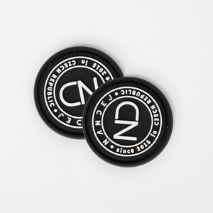 May include: Two black round coasters with white text. The coasters feature the letters "CN" and "ND" inside a circle, with the text "in Czech Republic since 2015" around the edge.