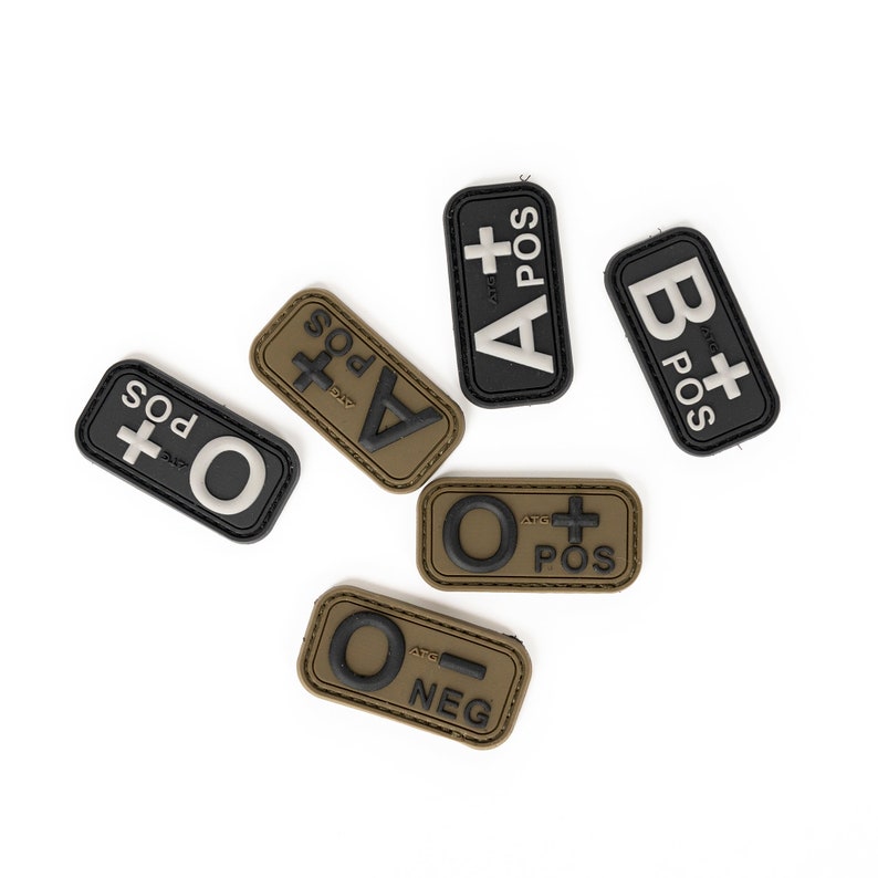 May include: Blood type patches in black, olive green, and tan. The patches display blood type information such as A+, B+, O+, and O-. The patches are rectangular with rounded corners and feature raised lettering.
