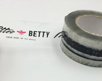 May include: Clear packing tape with a printed label that says "Petter Betty Throw Shade. Sip Tea. Repeat." The label has a pink bee graphic.