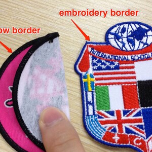 May include: Two embroidered patches, one with a circular merrow border and the other with an embroidered border. The circular patch is pink and white with a black merrow border. The other patch is a shield shape with a red, white, and blue embroidered border. The shield has a globe with a blue outline and the text "INTERNATIONAL SCHOOL OF SIENA" in a blue arc above the globe. The shield is divided into sections with different flags embroidered on each section.