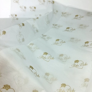 May include: White tissue paper with a gold heart and the words "Mika Bella" repeated throughout the paper.