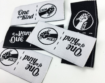 May include: Close-up of five white and black woven fabric labels with the text "One of a Kind" and a logo of a fist with the letters "CEW" inside a circle.