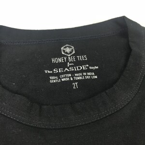 May include: Black tag with white text that reads "HONEY BEE TEES for The SEASIDE&reg; Style 100% COTTON - MADE IN INDIA GENTLE WASH & TUMBLE DRY LOW 2T". A bee with wings is in the top left corner of the tag.