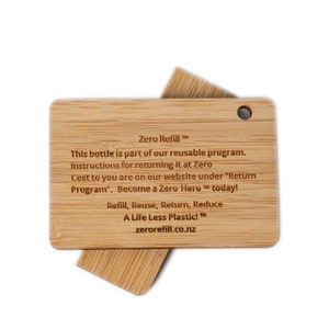 May include: A wooden tag with the text "Zero Refill" and instructions for returning a reusable bottle. The tag says "This bottle is part of our reusable program. Instructions for returning it at Zero Cost to you are on our website under "Return Program". Become a Zero Hero today! Refill, Reuse, Return, Reduce A Life Less Plastic! zerorefill.co.nz"
