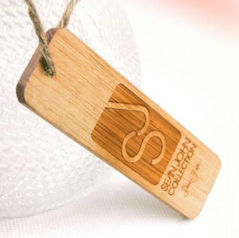 May include: A wooden tag with a brown rope attached. The tag has a logo with the letters "SJ" and the text "SEAN JOHN COLLECTION" printed on it.