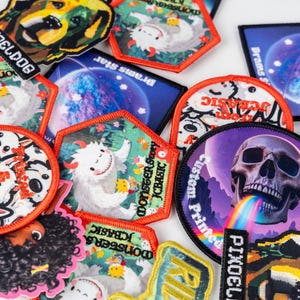 May include: A collection of colorful embroidered patches with various designs. The patches feature images of a dog, a skull with a rainbow, planets, and cartoon characters. Some patches have text like "PIXOELDOG" and "MONSTER STORY JCBASIC".