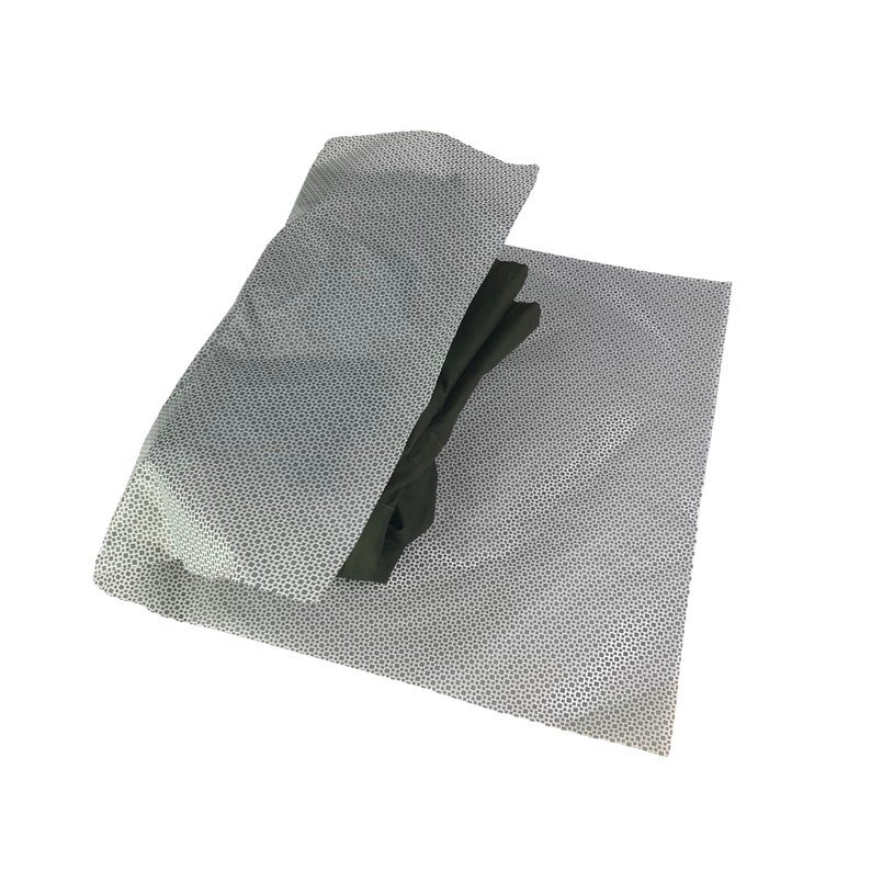 May include: A white tissue paper with a black and white pattern is folded over a stack of black fabric.