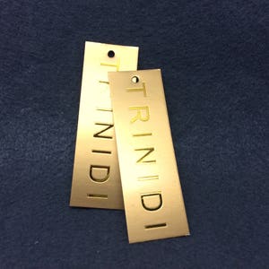 Pu&ograve; includere: Due etichette in metallo dorate con la parola "TRINIDI" in rilievo.