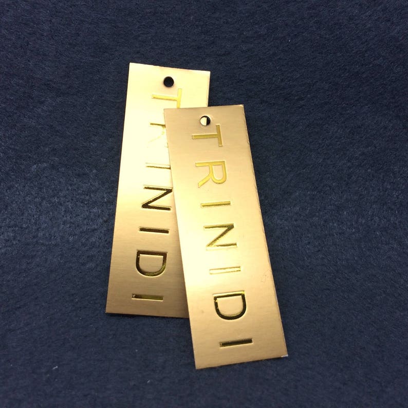 Pu&ograve; includere: Due etichette in metallo dorate con la parola "TRINIDI" in rilievo.