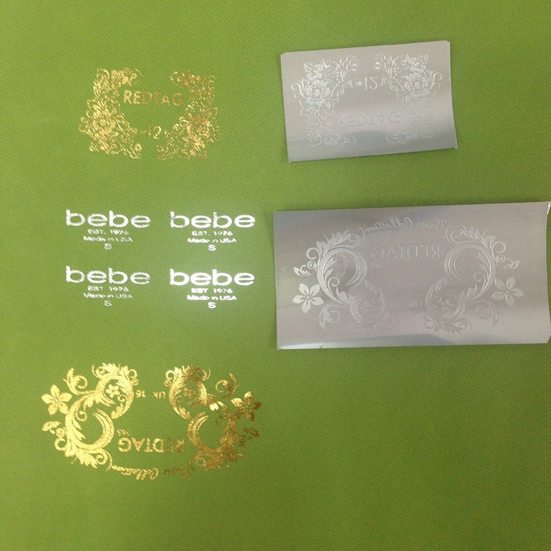 May include: Four silver and gold foil labels with a floral design. The labels have the text "REDTAG", "bebe EST. 1976 Made in USA S", and "KEDIVE".