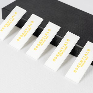 May include: Five white rectangular labels with the text "ESSENTIALS FEAR OF GOD" printed in gold letters.