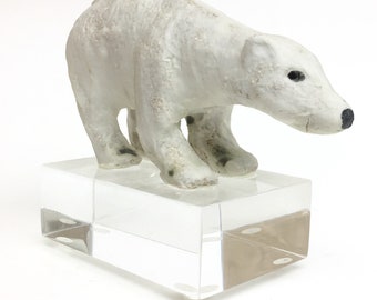 Prudence the baby polar bear the youngest of the pack handmade ceramic sculpture mounted on a acrylic ice cube block.