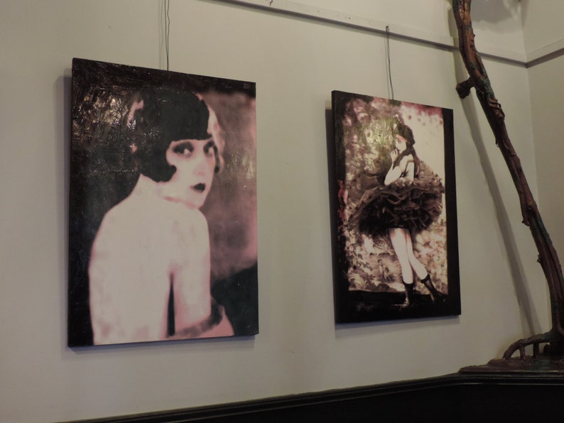 Puede incluir: Dos pinturas enmarcadas de mujeres. La pintura de la izquierda presenta a una mujer con el pelo corto y oscuro y un vestido rosa y blanco. La pintura de la derecha presenta a una mujer con un vestido negro con una falda con volantes.
