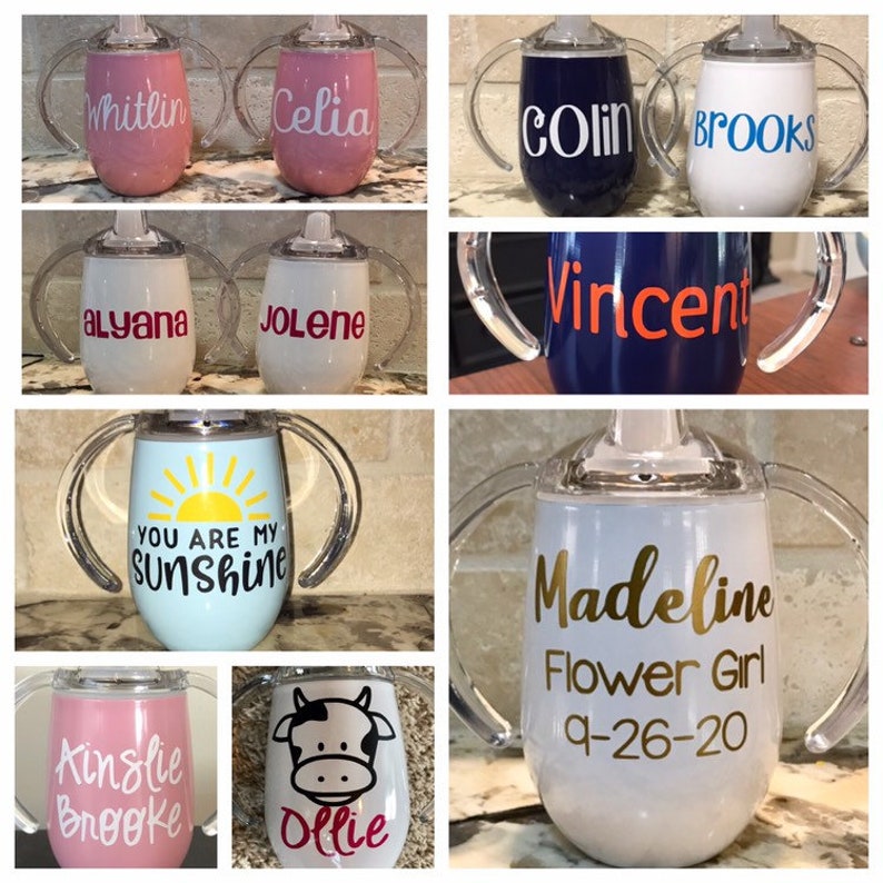 May include: Assortment of personalized sippy cups with various names, designs, and colors. The cups feature clear plastic handles and a variety of designs, including a sun, a cow, and text.