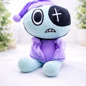 May include: A plush doll with a light blue body, purple shirt and hat, and a black eye patch with a white cross. The doll has a sad expression and large, round eyes. The doll is sitting down.