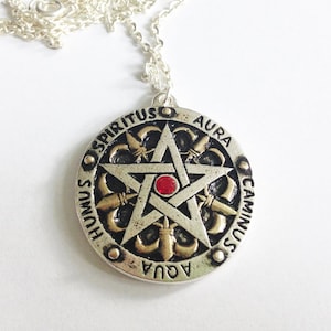 May include: Silver chain necklace with a round pendant featuring a five-pointed star with a red gem in the center. The pendant is inscribed with the words "Spiritus, Aura, Caminus, Humus, Aqua" in a circle around the star.