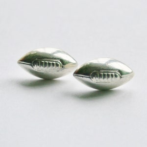 May include: A pair of silver football-shaped earrings.