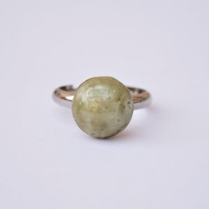 Op de afbeelding: Een zilveren ring met een grote, ovale, lichtgroene edelsteen.