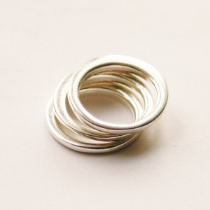 May include: A stack of five silver rings, each with a slightly different width, creating a layered effect.