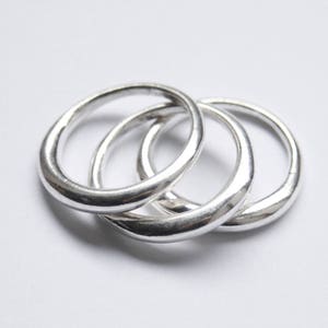May include: Three silver rings stacked on top of each other. The rings are smooth and have a rounded shape.