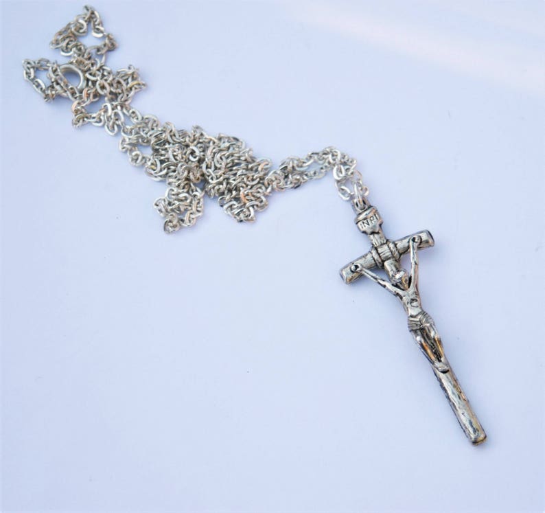 May include: A silver chain necklace with a silver crucifix pendant. The crucifix features a detailed figure of Jesus Christ.