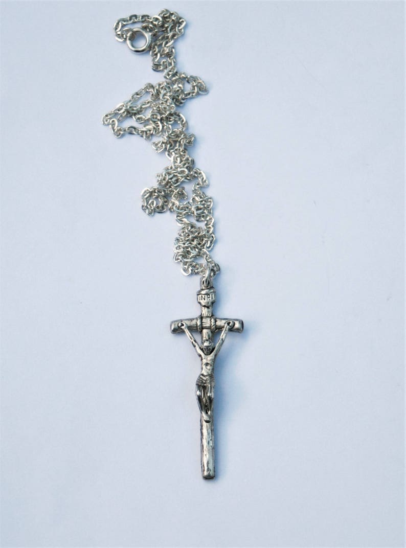 May include: A silver chain necklace with a silver crucifix pendant. The crucifix features a figure of Jesus Christ.