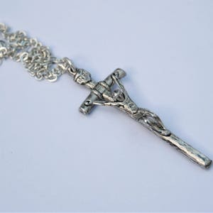 May include: A silver chain necklace with a silver crucifix pendant. The crucifix features a detailed depiction of Jesus Christ.