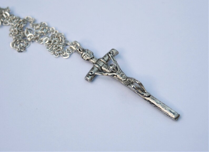 May include: A silver chain necklace with a silver crucifix pendant. The crucifix features a detailed depiction of Jesus Christ.