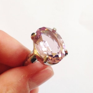 May include: A silver ring with a large, oval-shaped, light pink gemstone.