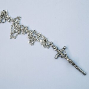 May include: A silver chain necklace with a silver crucifix pendant. The crucifix features a detailed figure of Jesus Christ.