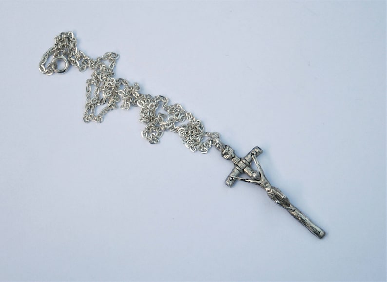 May include: A silver chain necklace with a silver crucifix pendant. The crucifix features a detailed figure of Jesus Christ.