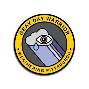 Pu&ograve; includere: Un adesivo circolare giallo con il testo "Gray Day Warrior Weathering Pittsburgh" attorno al bordo. All'interno del cerchio c'&egrave; una nuvola grigia con un occhio e una singola lacrima.